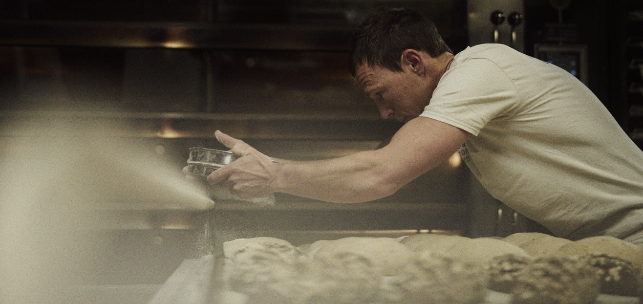 INOV8 Athlete Yannick Noel dusting loaves of bread in a commercial bakery.