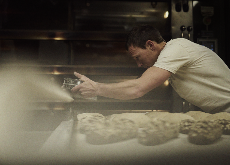 INOV8 Athlete Yannick Noel dusting loaves of bread in a commercial bakery.