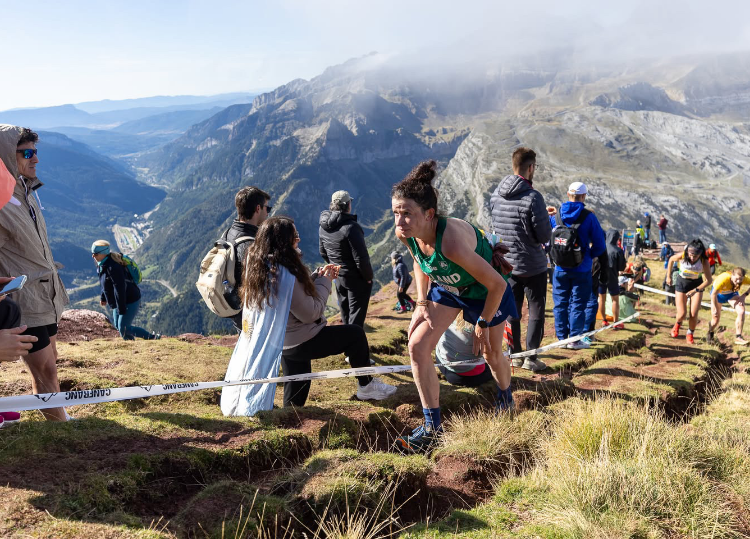 INOV8 Athlete Sarah McCormack climbing up a long, steep sunny mountain side