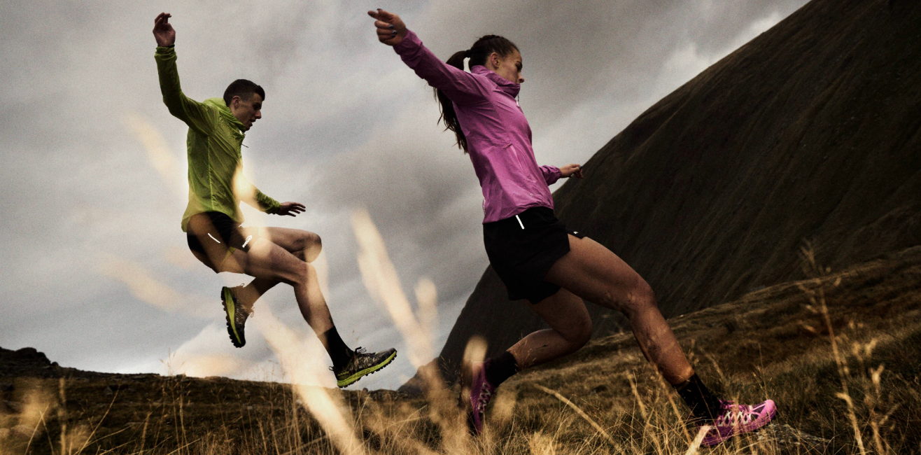 Runners in bright jackets jumping down a muddy fell, running fast