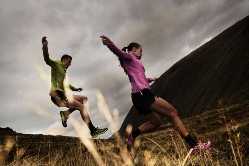 Runners in bright jackets jumping down a muddy fell, running fast