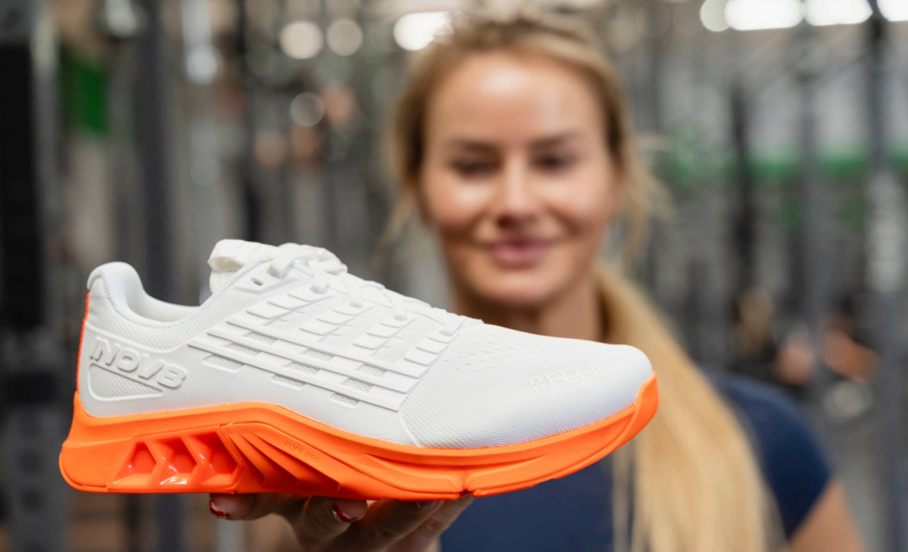 INOV8 Athlete Dani Speegle holding her exclusive orange and white F-LITE MAX shoe to camera