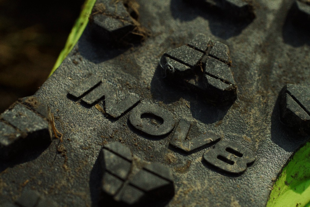 Close up shot of muddy aggressive lugs on the sole of a show