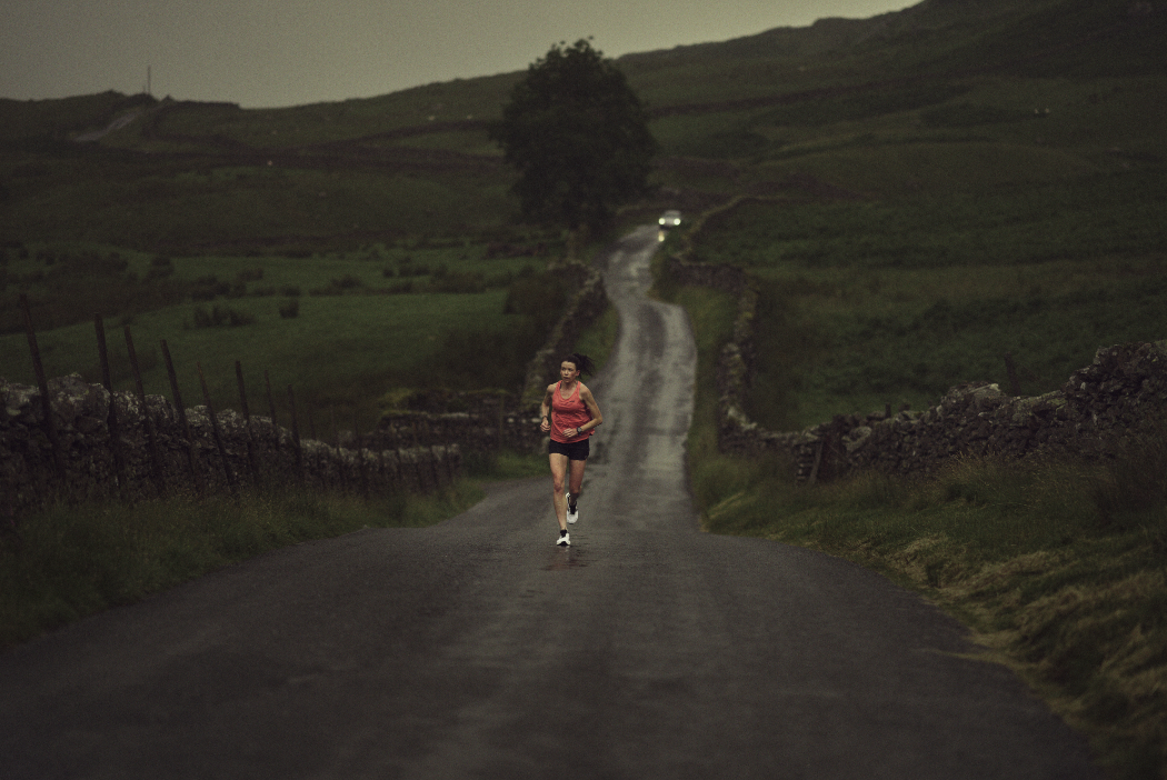 Sarah McCormack in the distance running on a long road in the rain