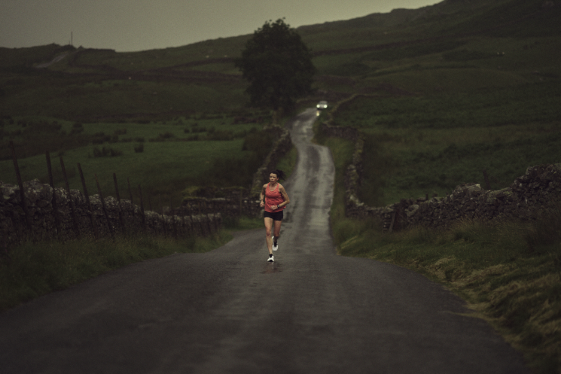 Sarah McCormack in the distance running on a long road in the rain