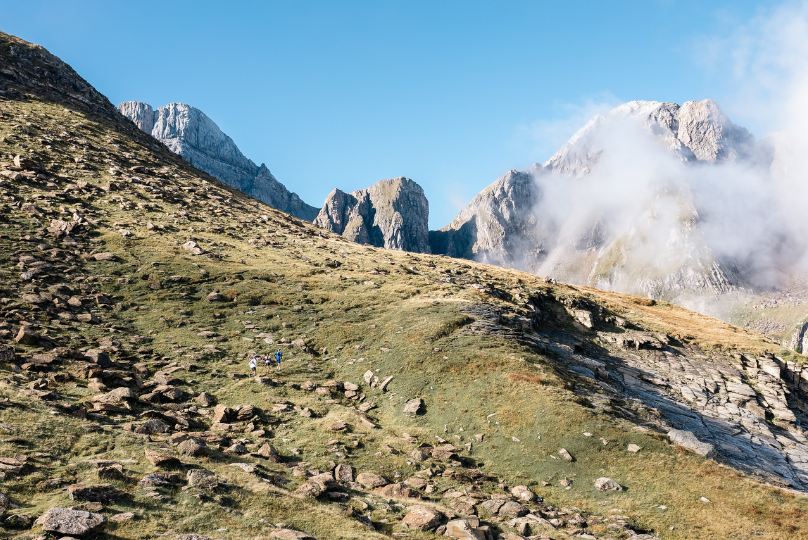 GB Athletes running down a green mountain slope with blue skies