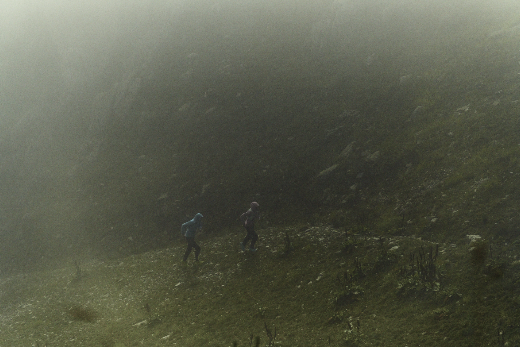 Runners running in the rain along a rocky path