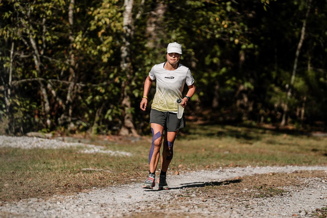 INOV8 Athlete Sarah Perry running with leg tape and carrying a flask
