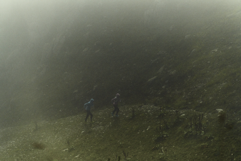 Runners running in the rain along a rocky path